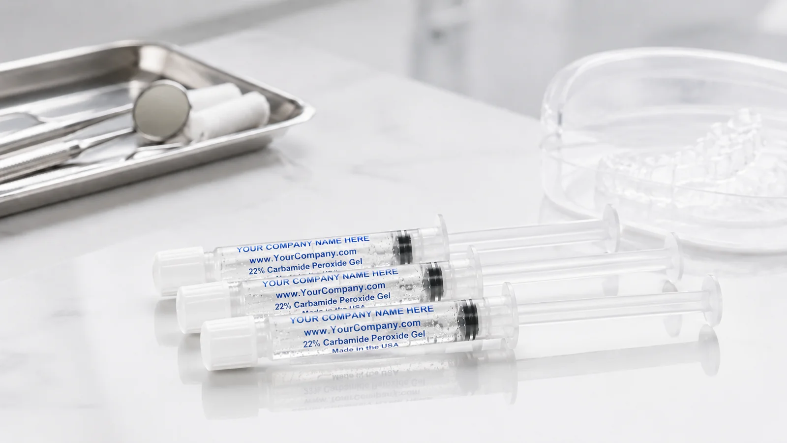 Three custom-print whitening gel syringes on a clinical counter beside dental trays
